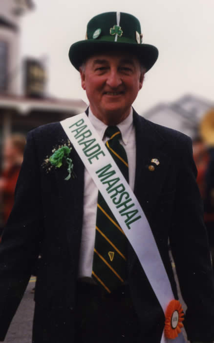 Picture of James Mahoney with Parade Marshal sash in front of Sig's